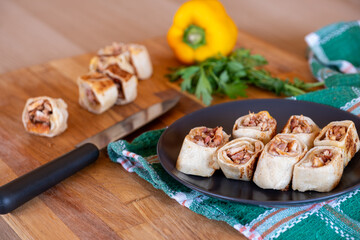 Shawarma pieces on wooden table with sweet peppers in the background and knife