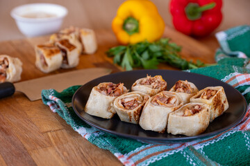 Shawarma pieces on wooden table with sweet peppers in the background and knife