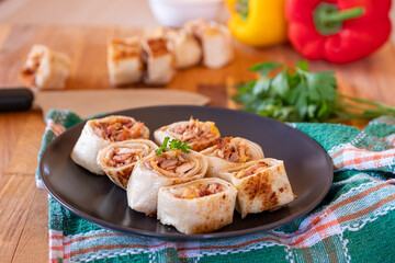 Shawarma pieces on wooden table with sweet peppers in the background and knife