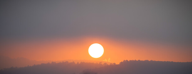 Sunset behind hills and trees, clouds looks like solar storm