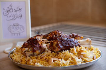 Plate of meat and rice topped with almonds on wooden table for eid adha saeed  translation : eid adha mubark