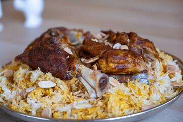 Plate of meat and rice topped with almonds on wooden table with top view