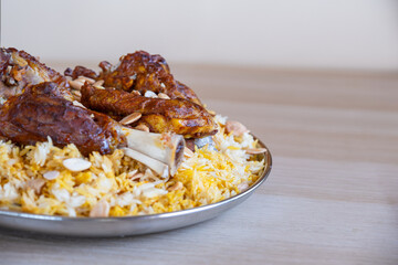 Plate of meat and rice topped with almonds on wooden table with top view