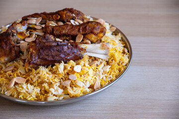 Plate of meat and rice topped with almonds on wooden table with top view