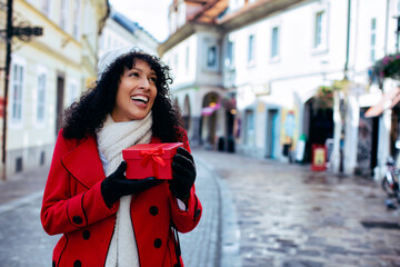 Fototapeta premium Woman Latina on street holding Christmas gift