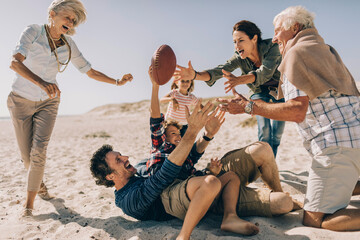 Multigenerational family playing American football on the beach