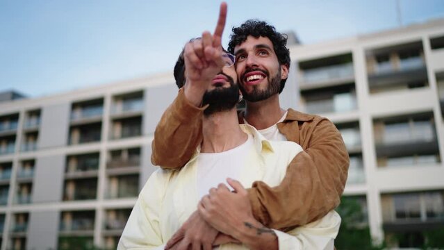 Carefree happy LGBT couple enjoying their vacations holidays while discovering touristic city places. Smiling gay men enjoying evening romantic date together in each other's hug arms