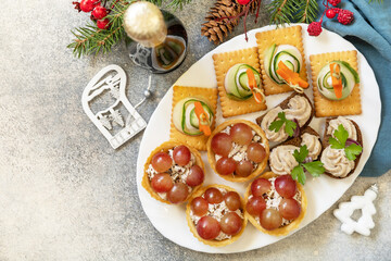 Creative appetizers set christmas. Christmas trees of ham, cucumber, cheese and star of carrot on crackers, tartlets with chicken and grapes, creamy pate sandwiches of herring on a rye bread.
