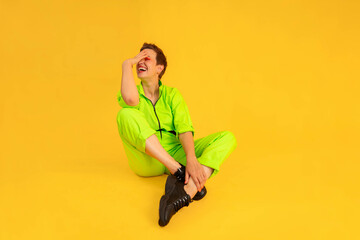 Middle age optimistic and Cheerful woman wear green overalls sitting on yellow color background....