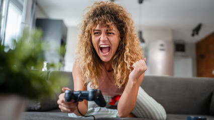 young woman play console video games hold joystick at home happy smile
