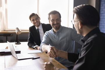 Happy businessmen make deal shake hands finish meeting, boss greeting company client handshaking,...