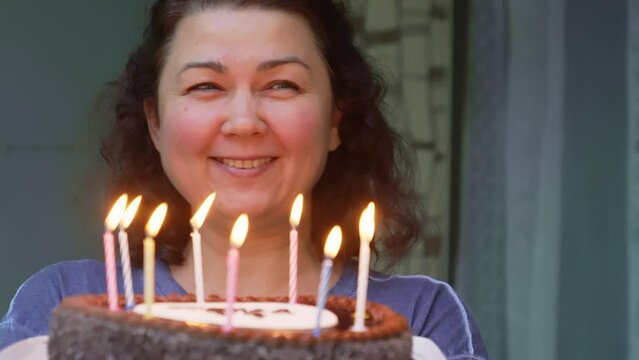 Middle-aged brunette woman with birthday cake with candles. 