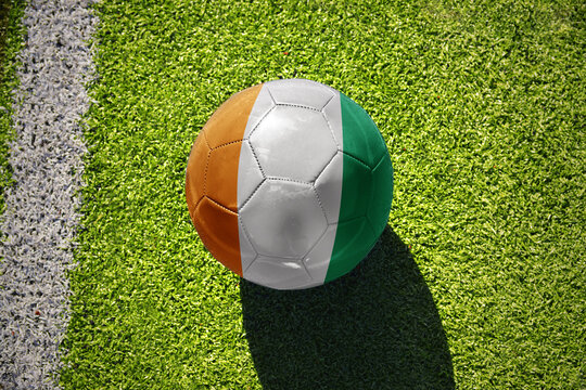 football ball with the flag of cote divoire on the green field near the white line