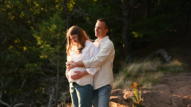 a pregnant woman and a young husband are hugging while holding an ultrasound scan near the pregnant belly. happy family concept. pregnant family on a walk