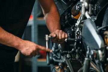 hands of professional person or mechanic working in workshop or garage with tools for auto or bike...
