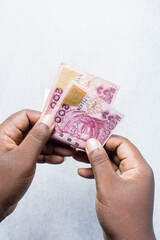 Hand holding the new Nigerian 200 Naira notes on a white surface, Hand holding Nigeria's new currency