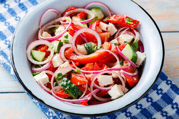 Bowl of vegetable salad with feta cheese on old boards. Close up