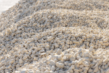 Crushed stone piles, a selected focus. Crushed stones for road repair. Hills of crushed stone in the sunlight. Bulk material for building roads or laying utilities