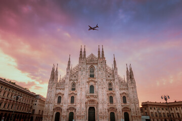 Milan Cathedral (Duomo di Milano) with blue and purple sky during sunrise with plane in flight