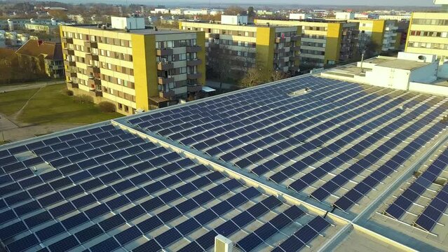 Solar power plant with blue photovoltaic panels mounted on commercial shopping store building roof for producing green ecological electricity. Production of sustainable energy concept