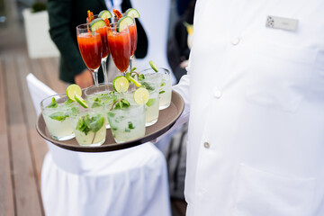 waiter carrying various cocktails 