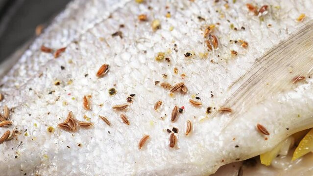 Raw stuffed dorado fish sprinkled with cumin seeds. Macro shot