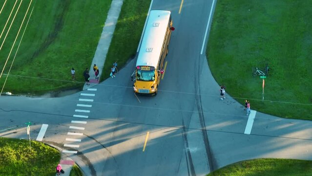 Standard American yellow school bus picking up kids at rural town street stop for their lessons in early morning. Public transport in the USA