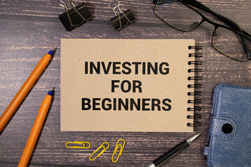 text Investing for Beginners on green sticker and wooden background