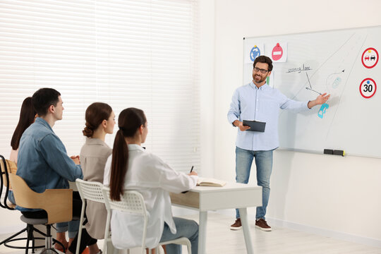 Teacher explaining traffic rules to audience during lesson in driving school