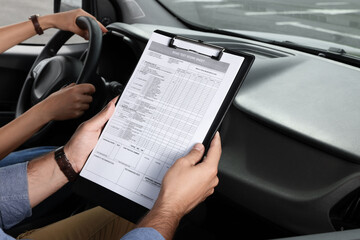 Driving school. Student passing driving test with examiner in car at parking lot, closeup