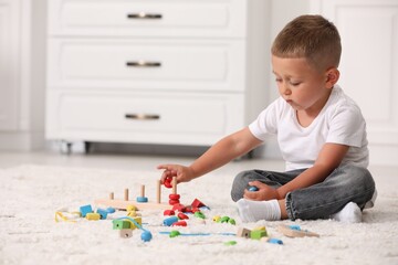 Motor skills development. Little boy playing with stacking and counting game on floor indoors