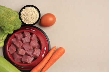 Raw meat in bowl and healthy products for pet on beige background, flat lay. Space for text