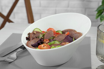 Delicious salad with beef tongue and vegetables served on table, closeup