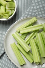 Fresh green cut celery on striped tablecloth, flat lay