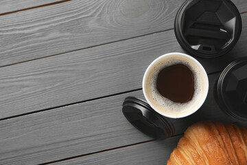 Coffee to go. Paper cups with tasty drink and croissant on grey wooden table, flat lay. Space for text