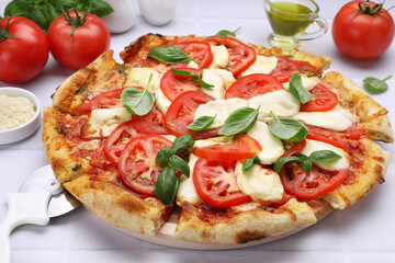 Delicious Caprese pizza with tomatoes, mozzarella and basil served on white tiled table, closeup
