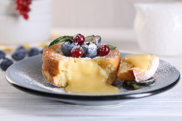 Tasty vanilla fondant with white chocolate and berries on light wooden table, closeup