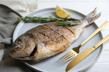Delicious baked fish served on white wooden table, closeup. Seafood