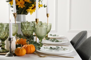 Beautiful autumn table setting with bouquet indoors. Plates, cutlery, glasses and floral decor
