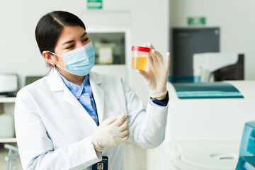 Woman chemist holding a urine test for medical exams in the lab - obrazy, fototapety, plakaty