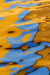 Vivid red, orange, blue and golden tones reflect in water on sunset in the river Spree in Berlin,...