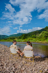 Fototapeta premium a couple of men and woman camping at the river in Nan Sapan Thailand, men and woman relaxing in the mountains of Northern Thailand looking out over the river