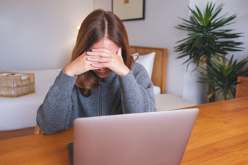 A woman get headache and stressed while working online on laptop computer at home