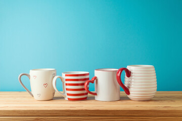 Coffee cups and tea mugs on wooden table over blue  background. Kitchen decoration