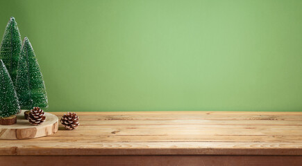 Empty wooden table with pine tree decoration over green background.  Christmas and winter holidays...