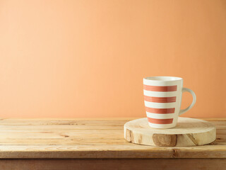 Coffee cup with log on wooden table over modern beige background. Kitchen mock up for design and product display