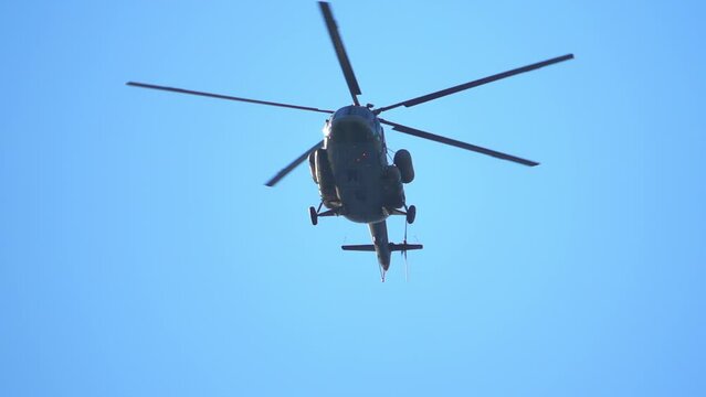 Helicopter flies against the blue sky, slow motion