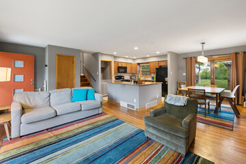 Clean, bright great room with couch, dining room and large windows