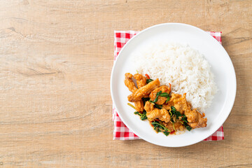 stir-fried fried fish with basil and chili in thai style topped on rice