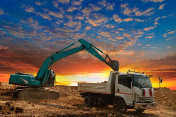 Crawler Excavator digging the soil into a truck ,In the construction site on the sunset sky...